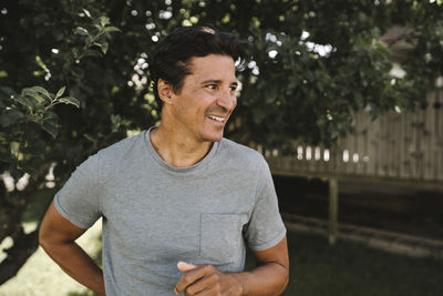 Smiling man looking away in front yard