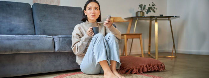 Portrait of young woman sitting on sofa at home