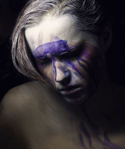 Close-up portrait of a young sad woman with colorful face painting