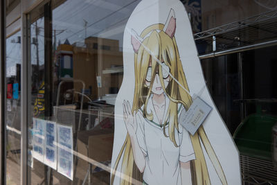 Reflection of woman standing on glass window in store