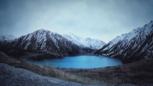 Scenic view of lake and snow covered mountains against sky