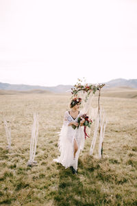 Woman standing by tree on field against sky