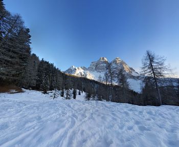 Snow covered landscape against clear blue sky