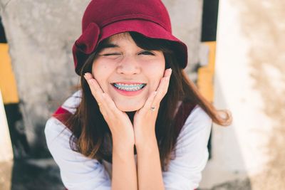 Portrait of smiling young woman with hands on chin sitting outdoors