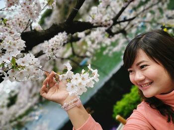 Smiling young woman looking at white flowers