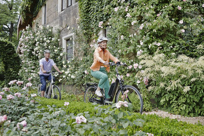 People riding bicycle on flowering plants