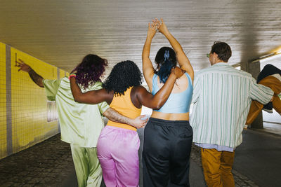 Rear view of male and female friends enjoying with each other while walking on underpass
