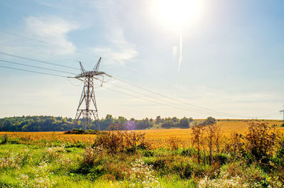 High voltage power lines on background of blue sky and green vegetation.