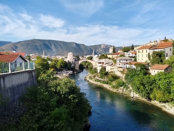 View of townscape by river in town against sky