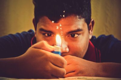 Close-up of teenage boy with lit cigarette lighter