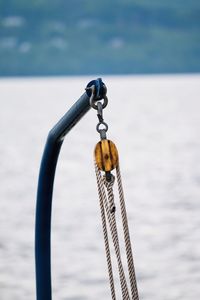 Close-up of chain hanging on rope against sea