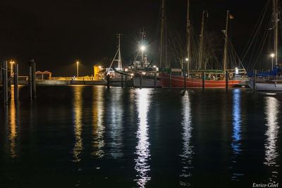 Boats moored at harbor against sky at night