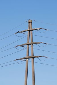 Low angle view of electricity pylon against clear sky