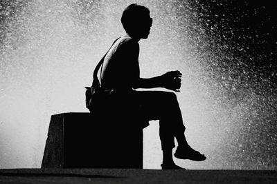 Side view of woman sitting on seat while water splashing in lake