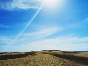 Scenic view of arid landscape against blue sky