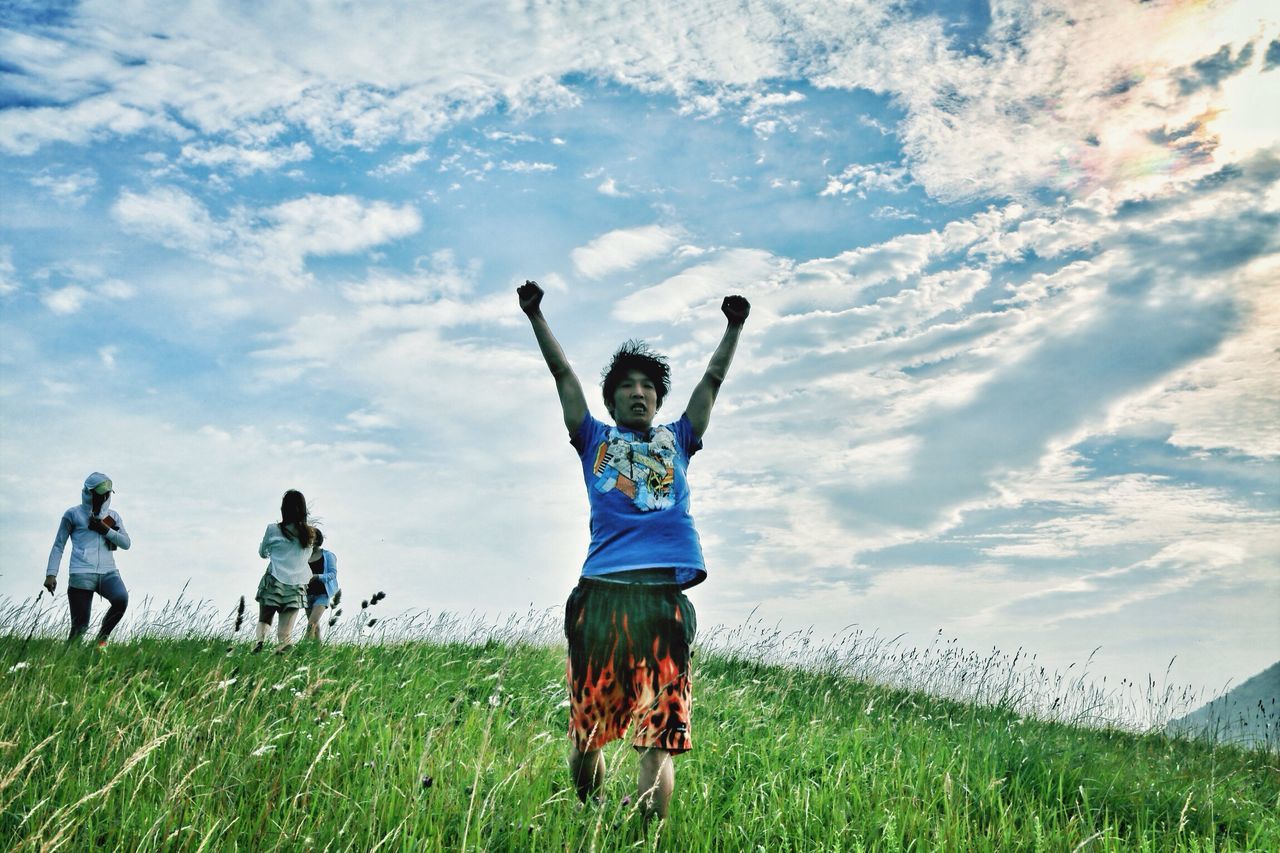 grass, leisure activity, lifestyles, full length, field, sky, enjoyment, men, cloud - sky, fun, grassy, togetherness, casual clothing, green color, playing, bonding, mid-air, sport, landscape