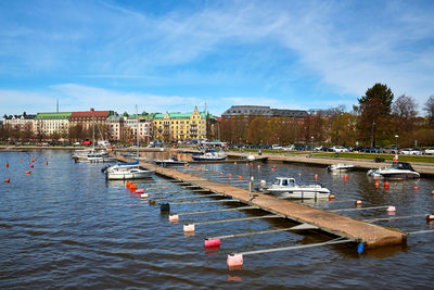 Sailboats moored on river by buildings against sky