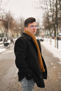 Portrait of young man standing on street in city