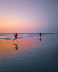 Siblings running on shore at beach