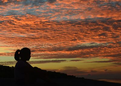 Silhouette man on shore against sky during sunset