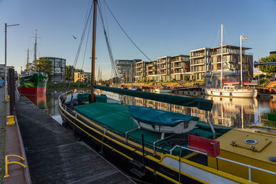 Boats moored at harbor against sky in city