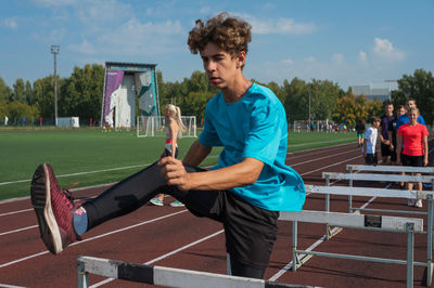 Portrait of young man exercising on field