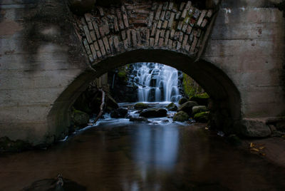 River flowing through arch bridge