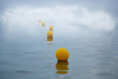 Yellow floating on water in lake against sky