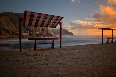 Lifeguard hut on beach against sky during sunset