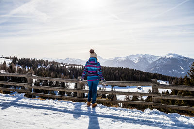 Rear view of woman standing on snowcapped mountain against sky