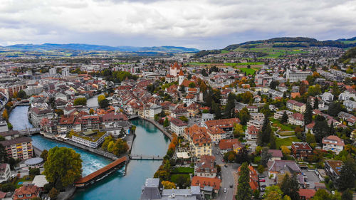 High angle view of illuminated city by river against sky