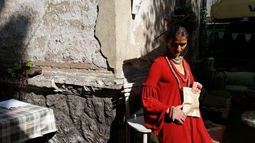 Mature woman holding paper bag while sitting on chair by wall