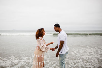 Friends standing on beach against sky