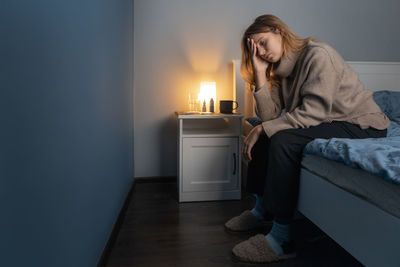 Depressed woman sitting on bed at home