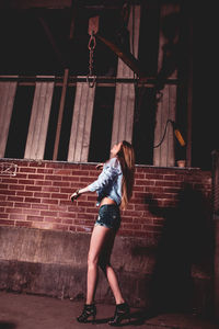 Female model posing against wall at night