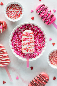 A sweet cakesicle in a bowl of sprinkles surrounded by cakesicles and sprinkles