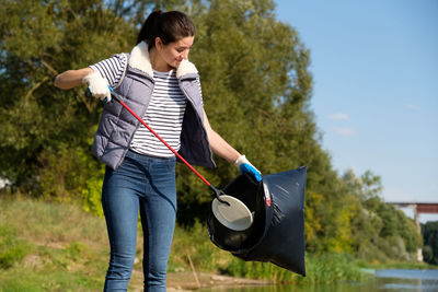 Young woman putting garbage in plastic