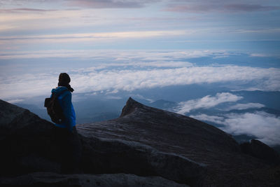 Rear view of man standing on mountain against sky