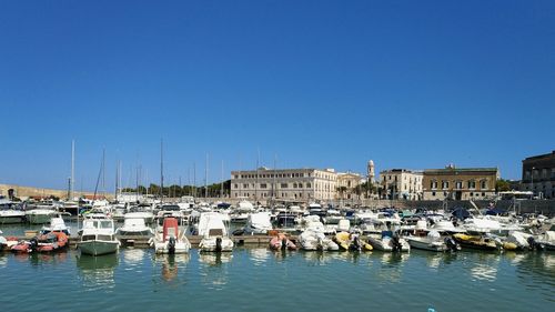 Boats moored in harbor against clear sky