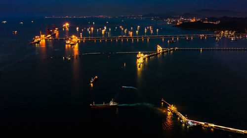 Firework display over river in city against sky at night