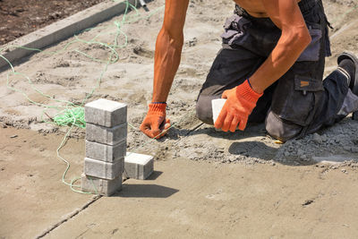 A worker sets the level with a stretched nylon thread for laying paving slabs.