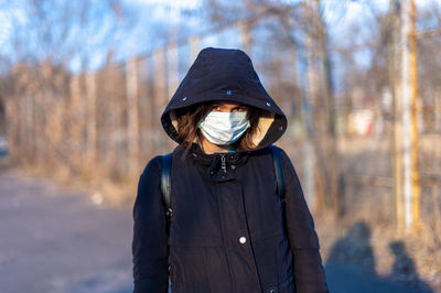 Woman standing in park covered face in the mask during autumn