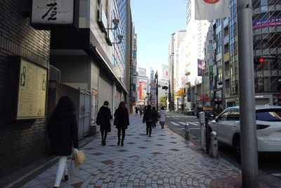 People walking on footpath amidst buildings in city