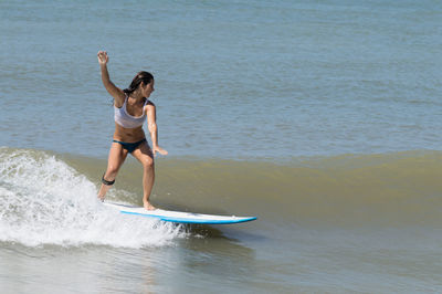 Young woman surfboarding in sea