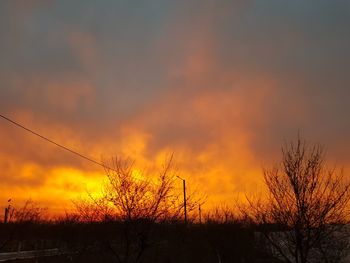 Silhouette bare trees on landscape against romantic sky at sunset