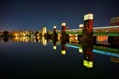 Illuminated bridge over river in city at night