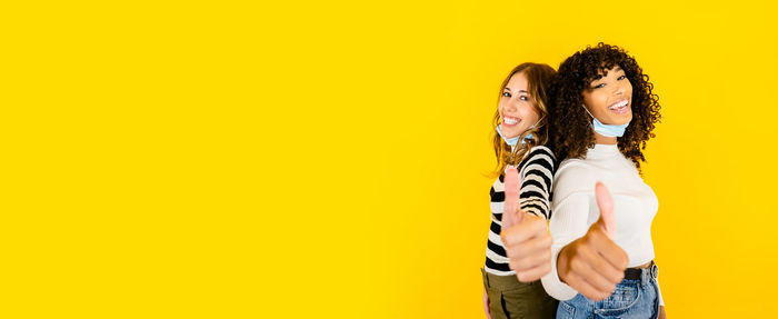 Portrait of a smiling young woman against yellow background