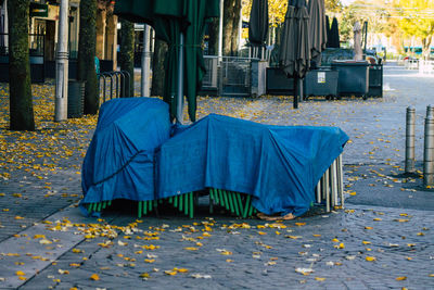 Empty chairs on sidewalk in city during autumn