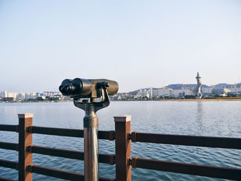 Coin-operated binoculars by sea against clear sky