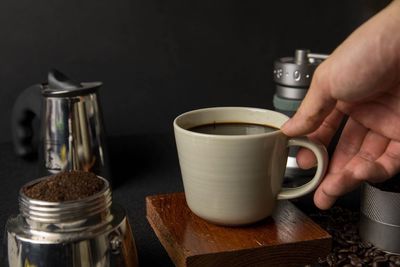 Cropped image of hand holding coffee cup on table